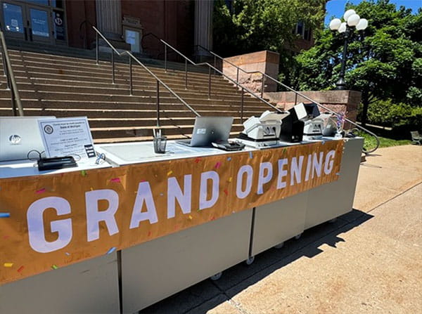 A banner reads "Grand Opening" at the ribbon cutting