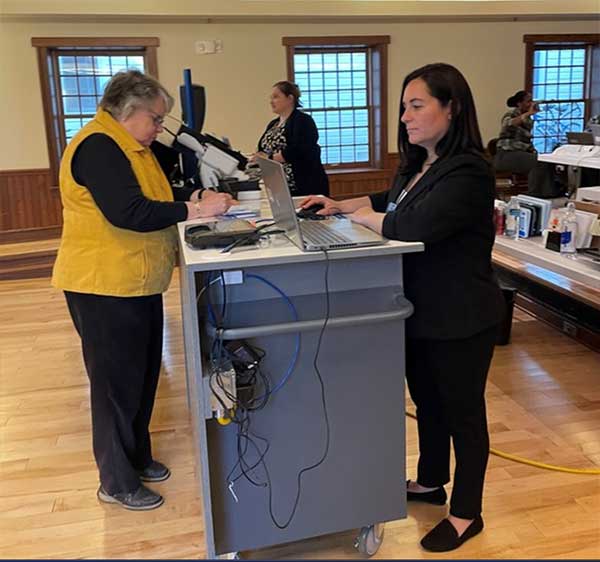 Secretary of State mobile office staff assist Mackinac Island Mayor Margaret Doud (L) with her license plate and driver's license renewals