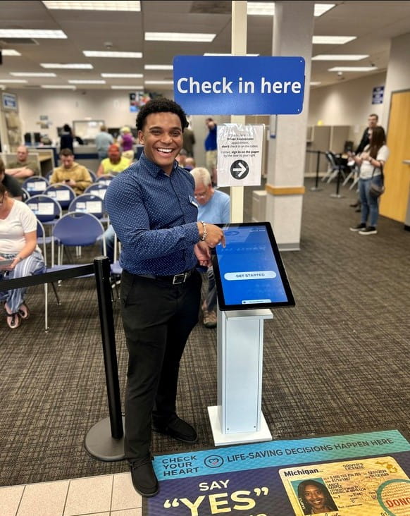 Portage Manager Xavier Henderson smiles next to new check-in station