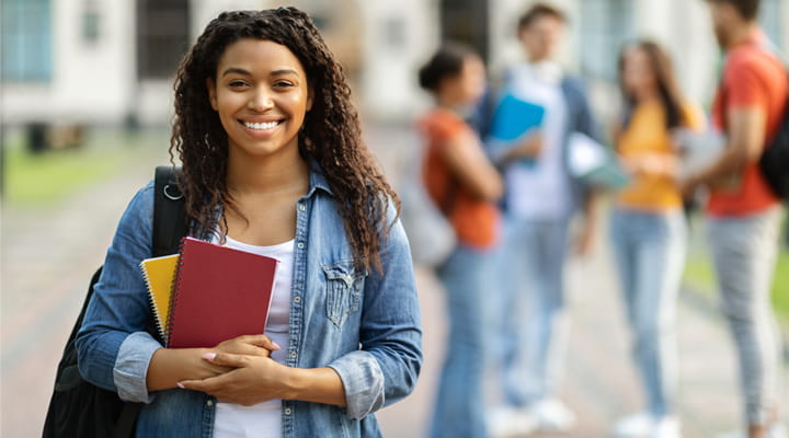Happy, smiling female student holding books outside of class