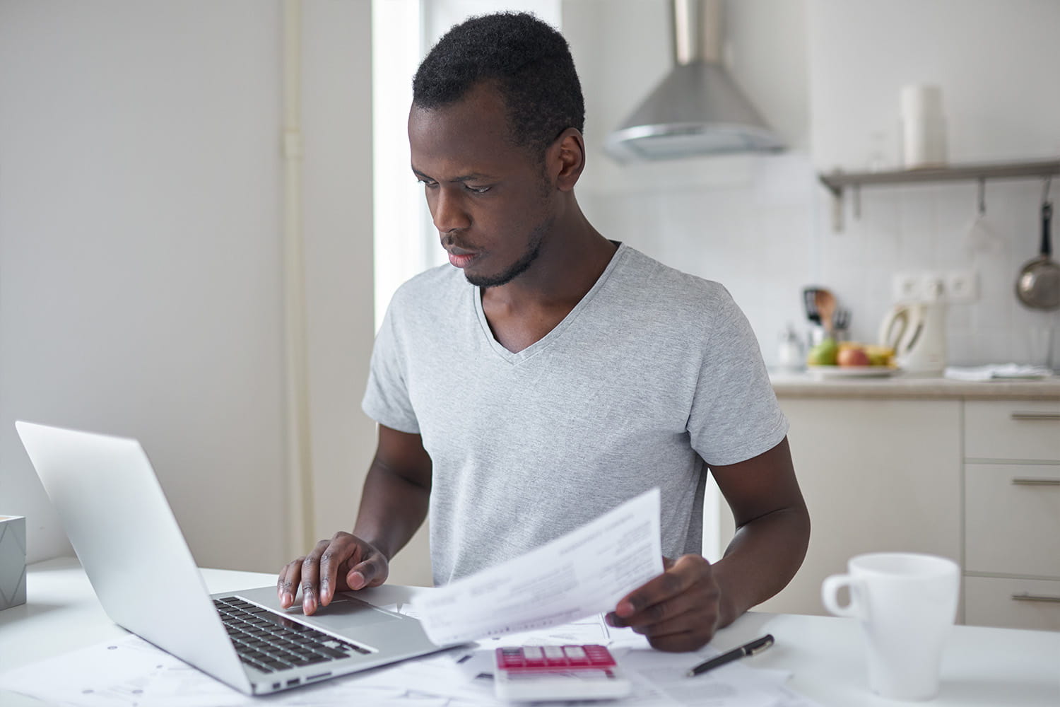 Man holding a bill and looking at his computer