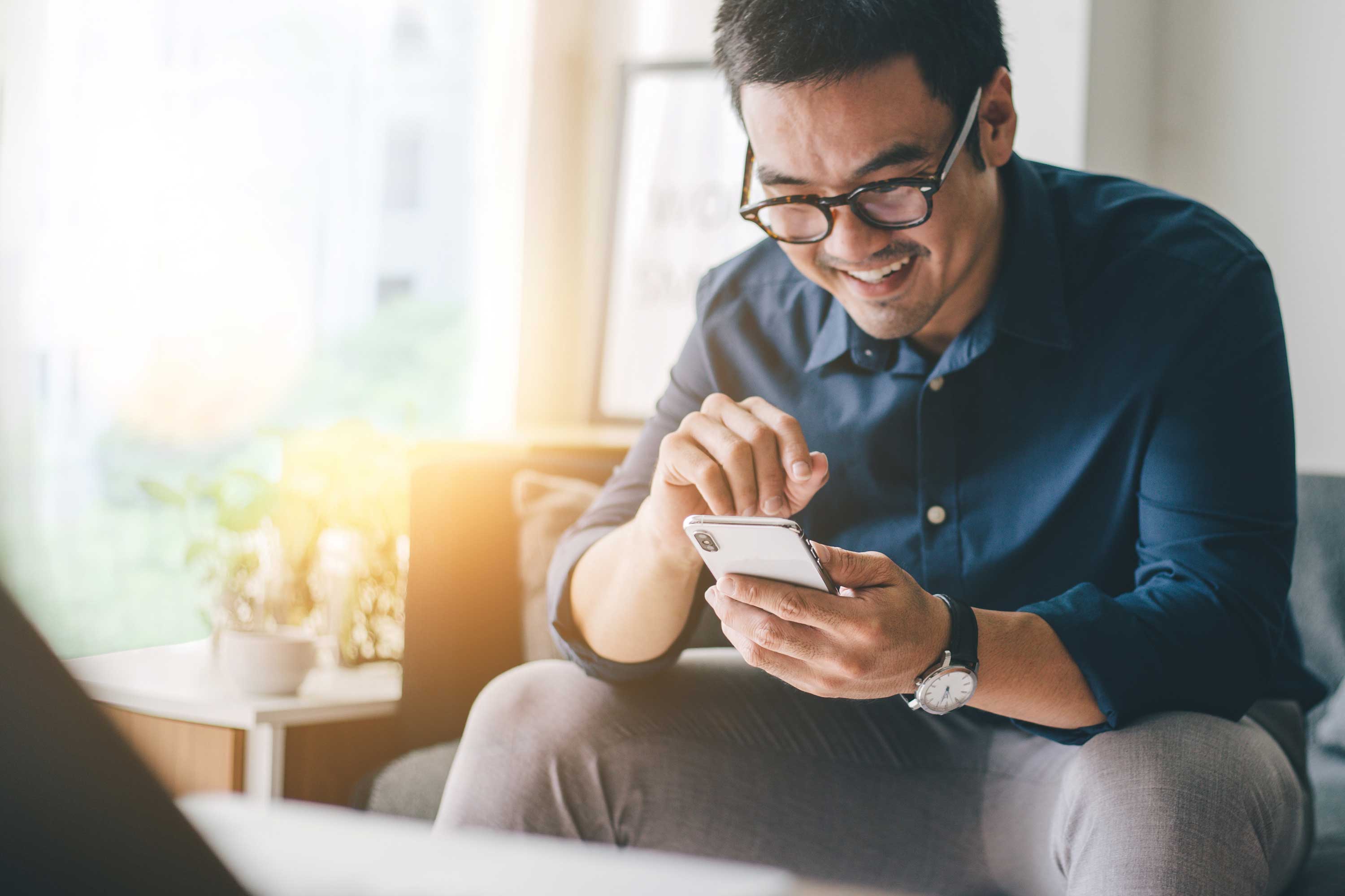 A smiling man using a smart phone.