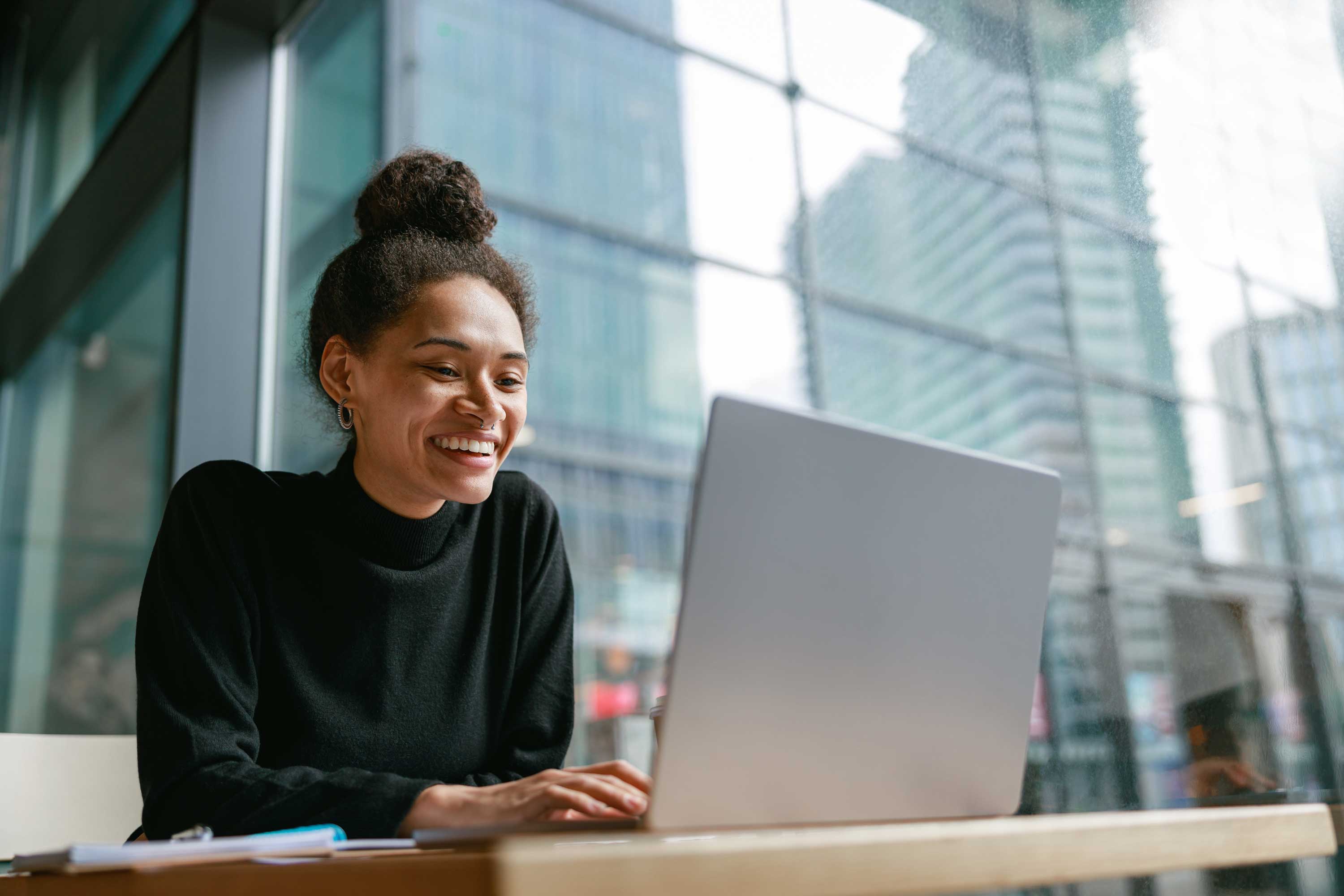 A smiling woman of color using a laptop computer.
