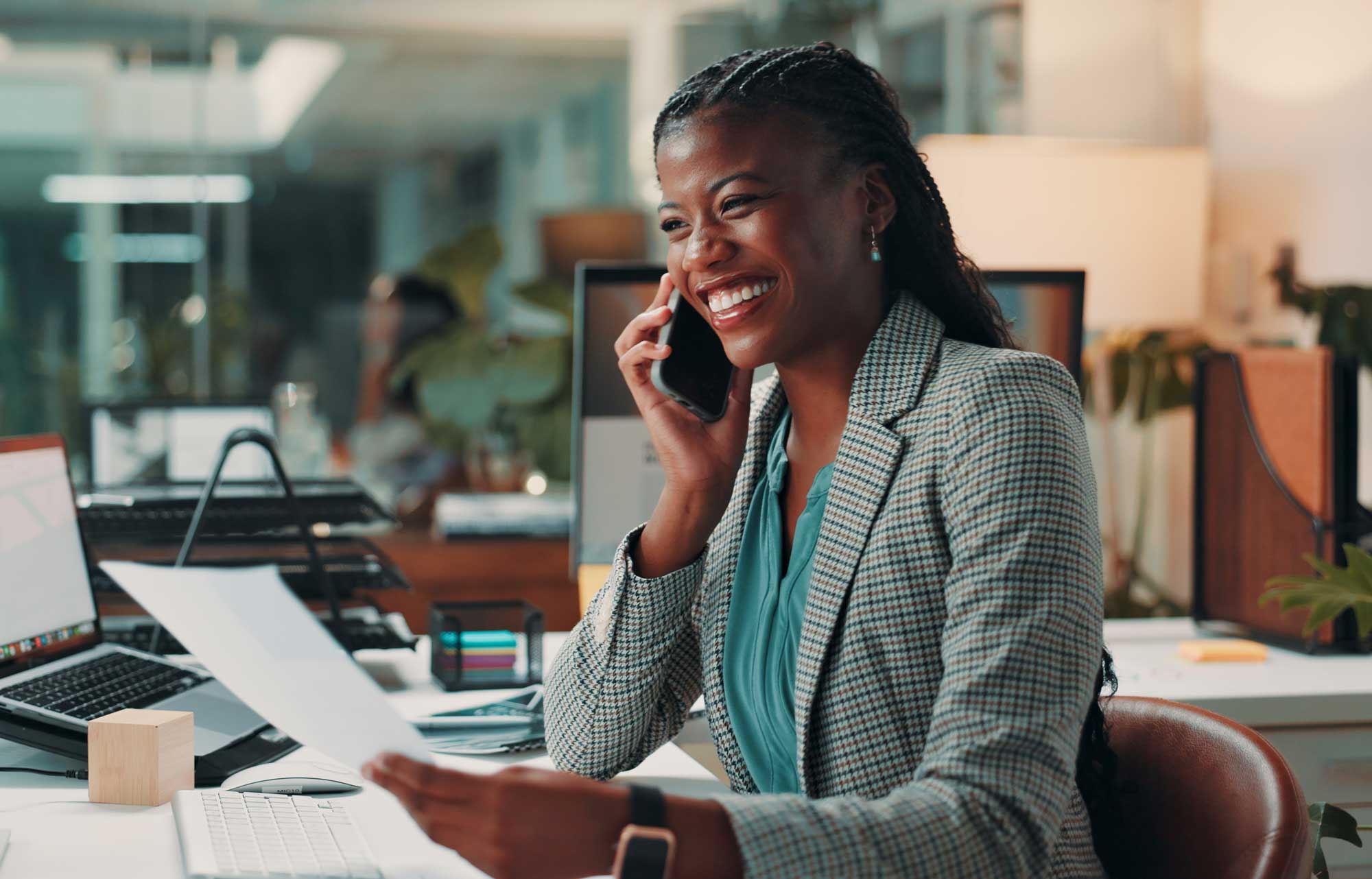 A smiling woman of color talking on a cellphone.