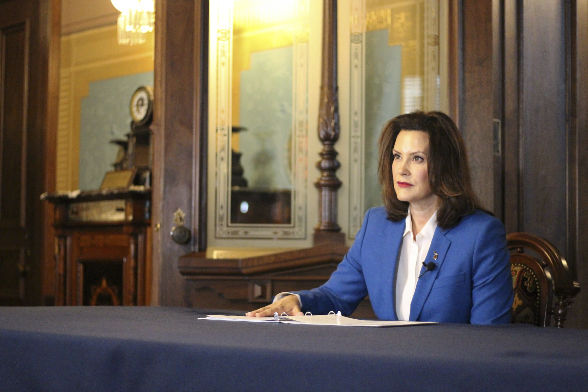 Photo of Governor Whitmer sits at a desk during a press conference.