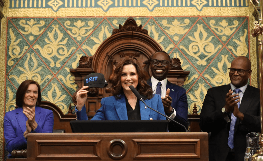 2023 SOTS image of Gov. Whitmer holding up a hat with the word "GRIT" on it.